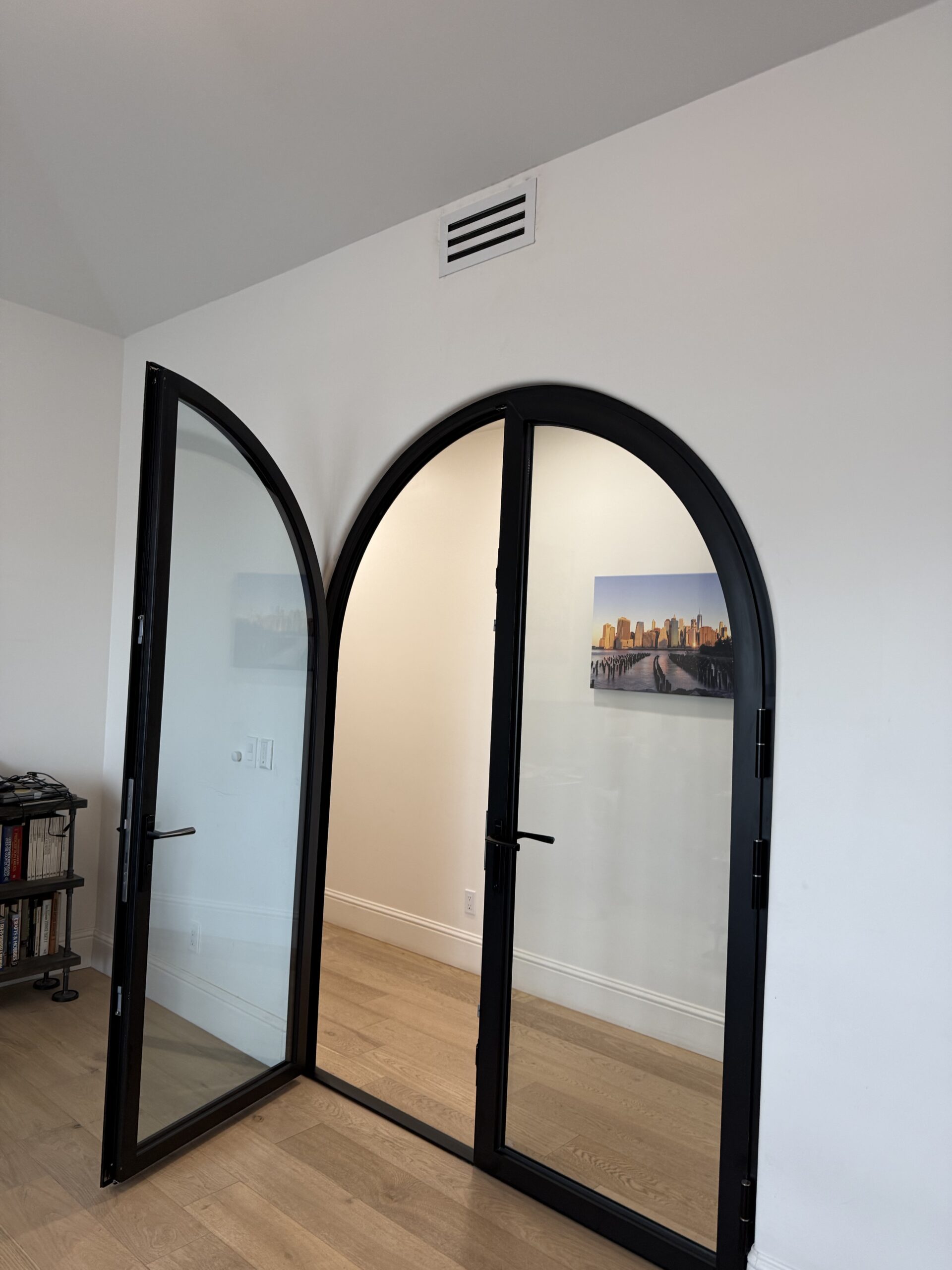 Arched black iron double doors in a hallway